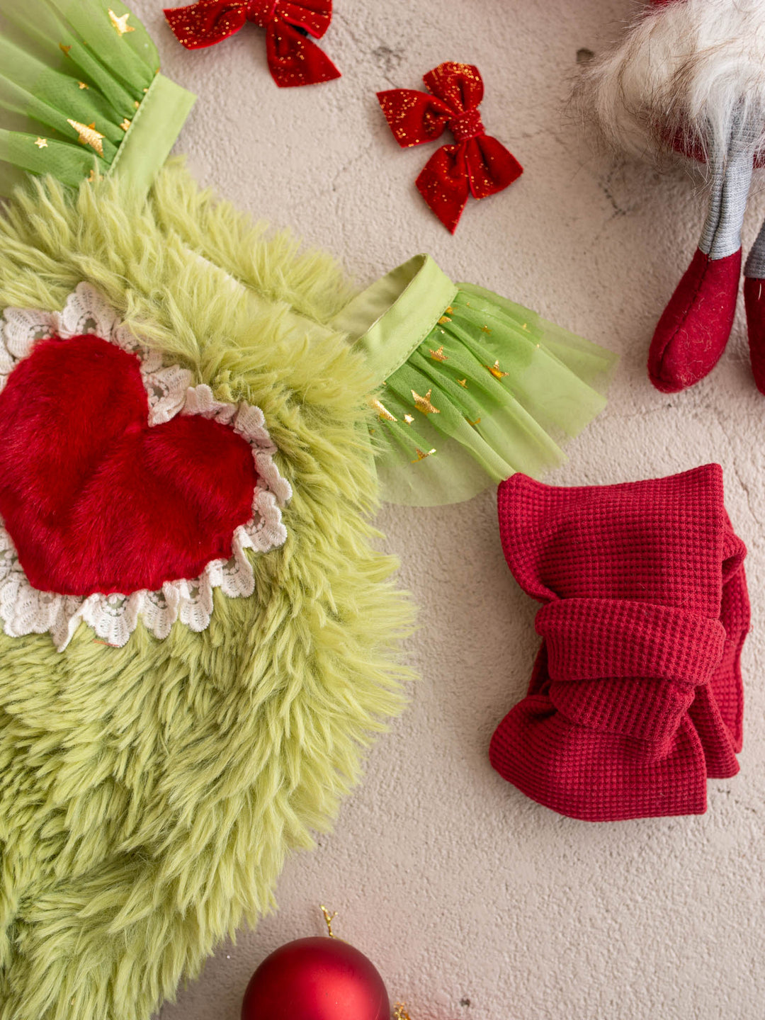 Close-up of the red fur heart and lace trim on the Little Grump green faux-fur romper with red leg warmers - Before & Ever Kids