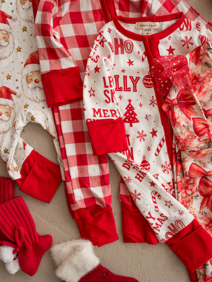 All I Wish Christmas baby onesies laid out together including the Jolly print - Before & Ever Kids