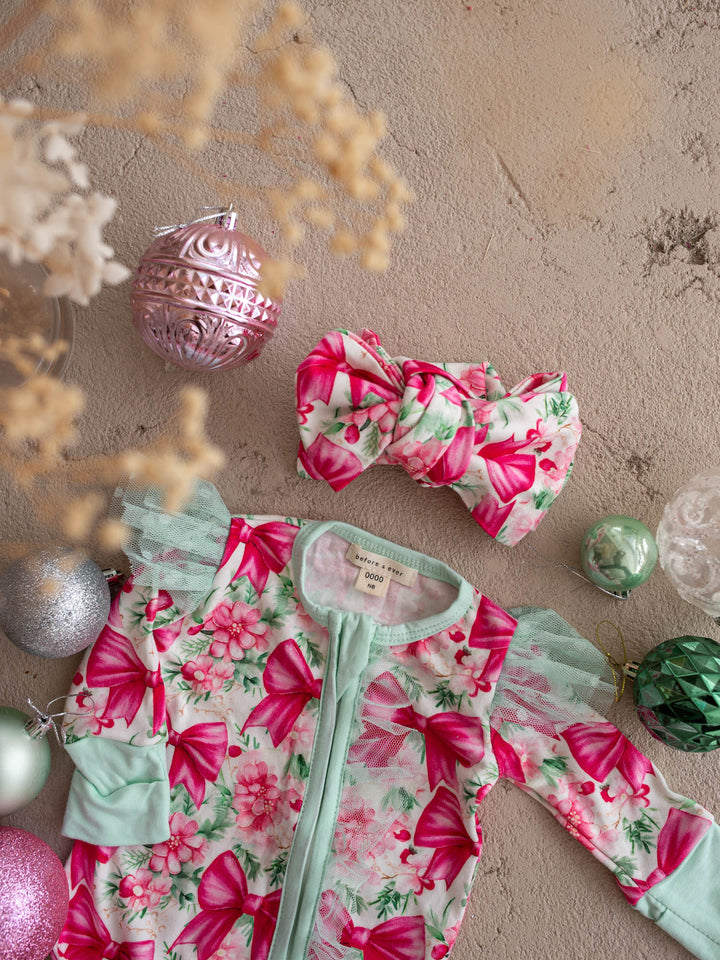 All I Wish Christmas baby onesies and topknots laid out together including the Pink Bow print - Before & Ever Kids