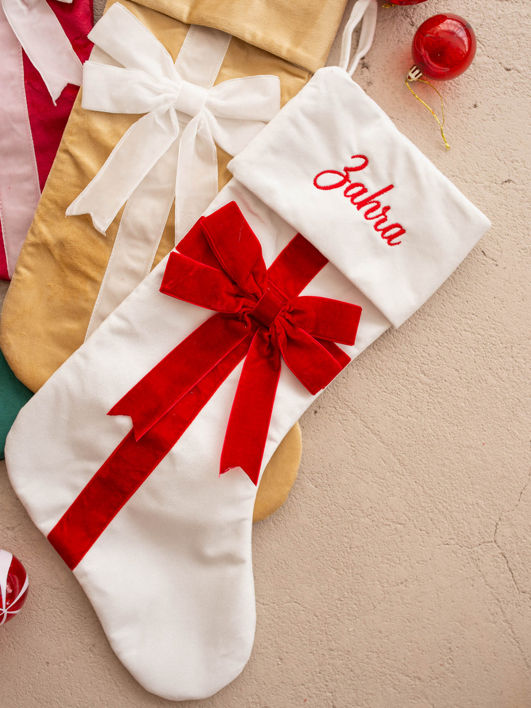 All Wrapped Up personalised Christmas stocking, white, gold and red stockings overlapping, close on the bows - Before & Ever Kids