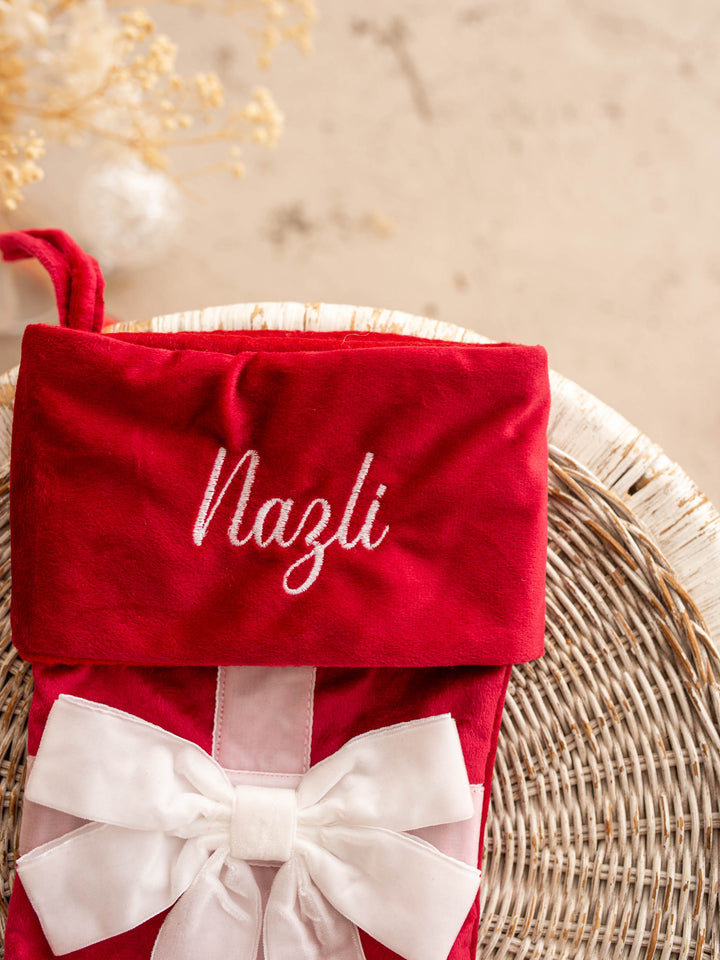 All Wrapped Up personalised Christmas stocking, close up of the red stocking's embroidered name and white bow - Before & Ever Kids