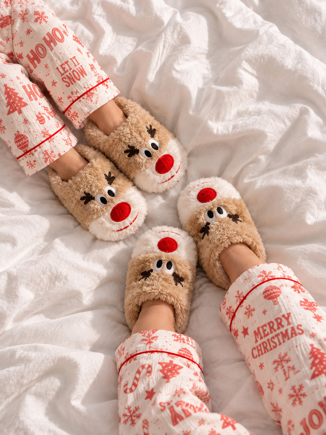 Baby Rudolph Slippers tan plush reindeer slippers with antlers and a red nose, worn on a bed - Before & Ever Kids