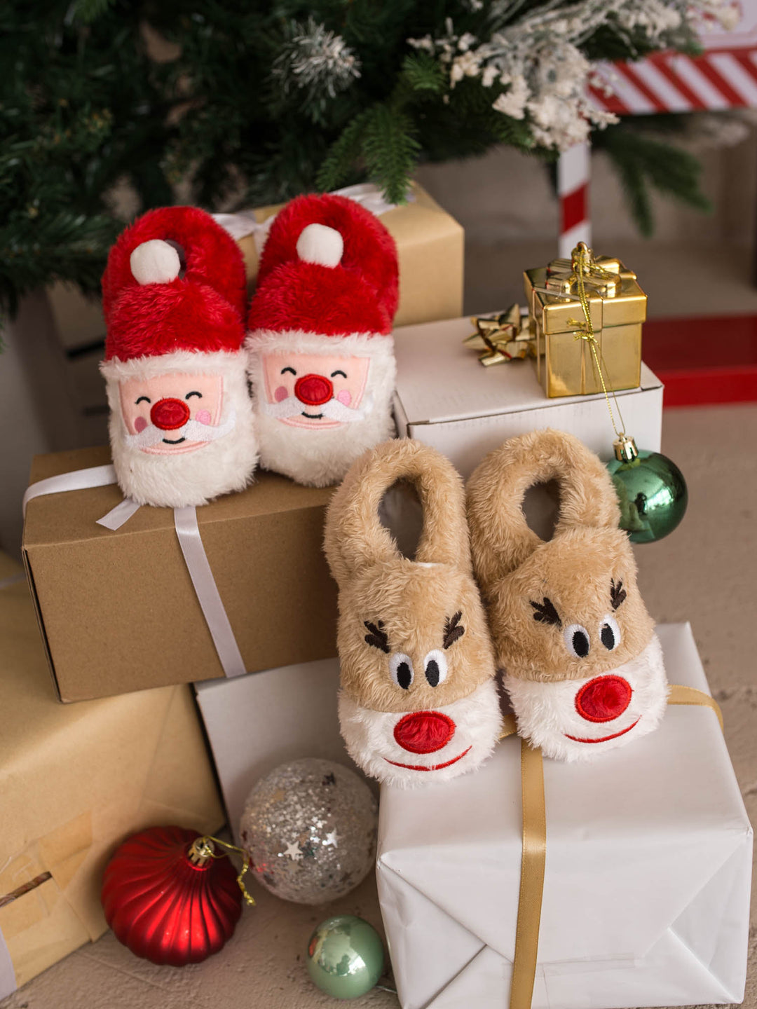 Baby Rudolph Slippers and Santa Baby Slippers stacked on gift boxes - Before & Ever Kids