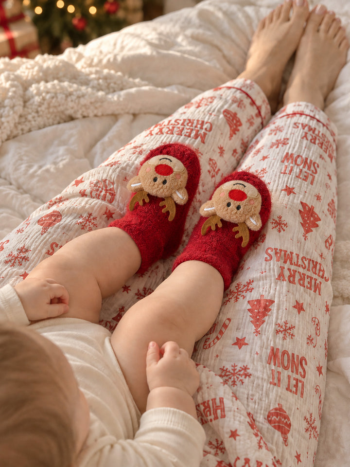 Baby Rudolph red fluffy socks with brown antlers and a red nose, worn by a baby beside an adult in Christmas pyjamas - Before & Ever Kids