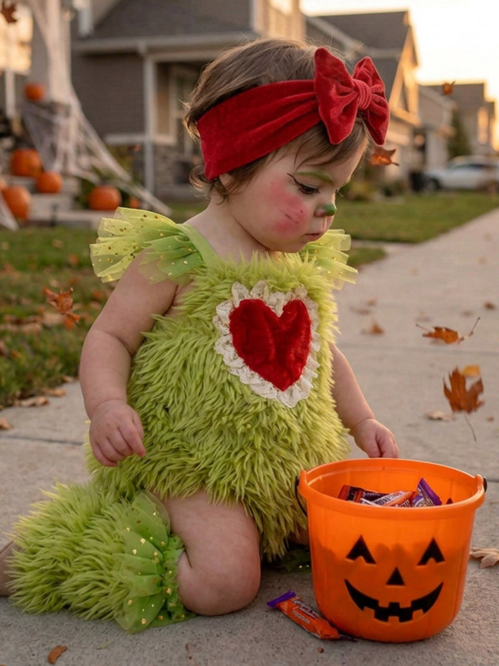 Little Grump green faux-fur romper with red heart on baby kneeling beside a pumpkin candy bucket - Before & Ever Kids