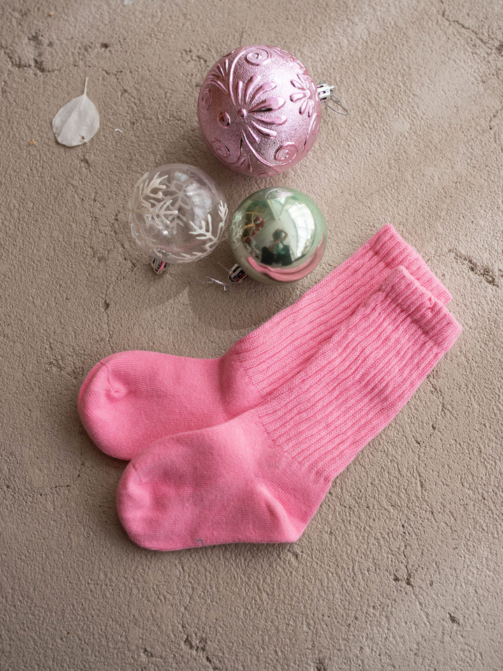 Bubblegum pink ribbed knit socks laid flat beside pink and mint Christmas baubles