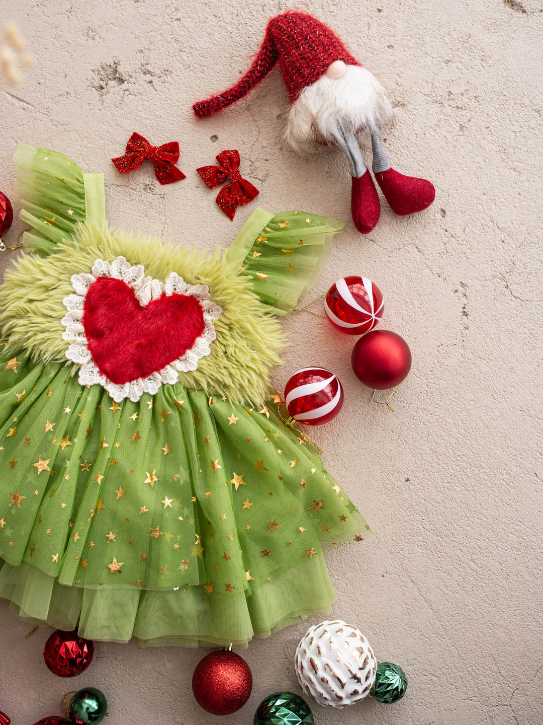 Miss Grump green tulle dress with gold stars and a red fur heart, surrounded by red and green Christmas baubles - Before & Ever Kids