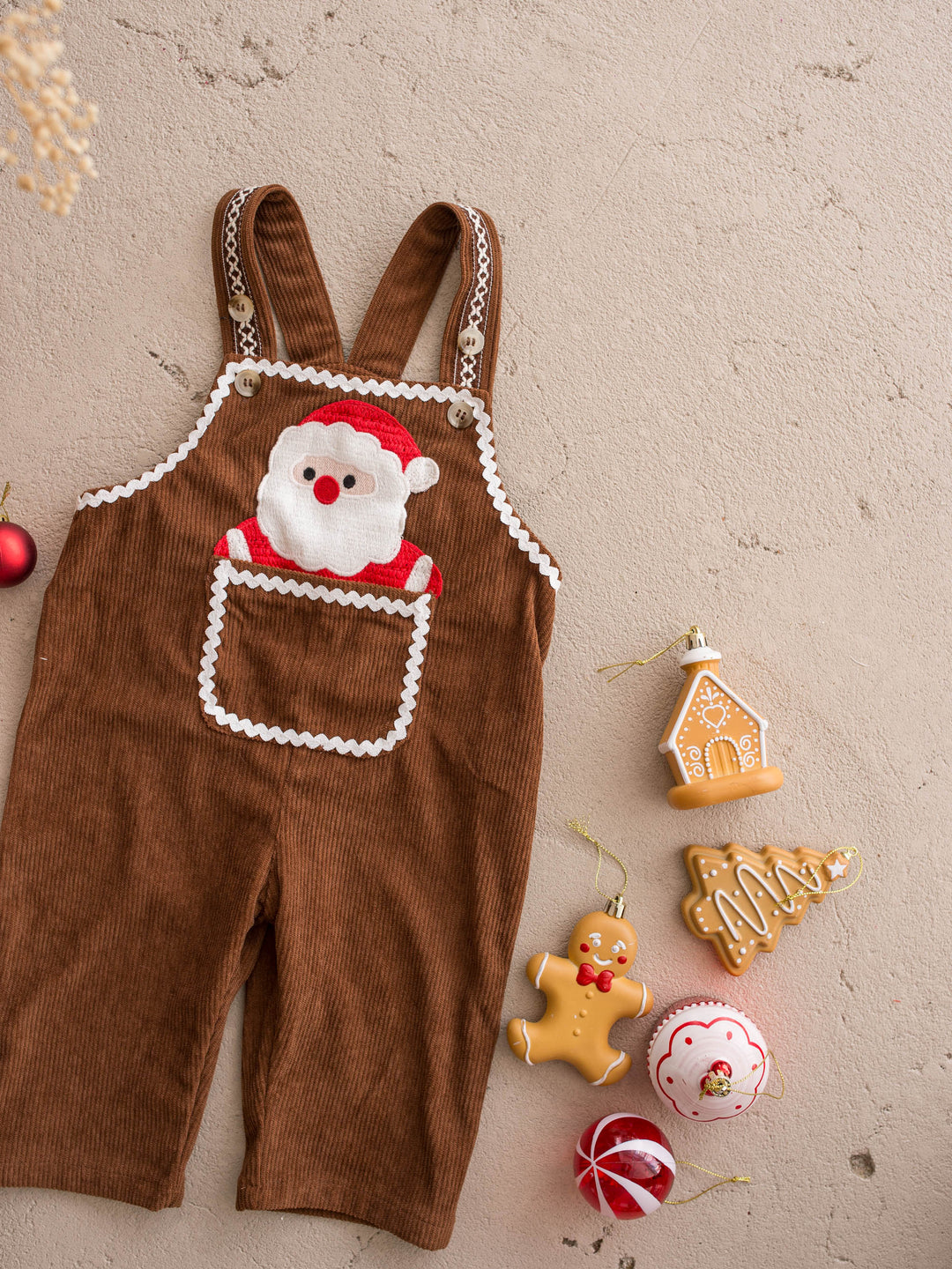 Peekaboo Overall in Santa, chocolate cotton corduroy overall with a Santa face pocket, flat with gingerbread cookies and baubles - Before & Ever Kids