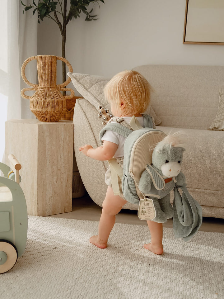Sage the Horse personalised Little BFF Companion Backpack, toddler walking across the living room wearing the backpack, horse plush and comforter on the front - Before & Ever Kids