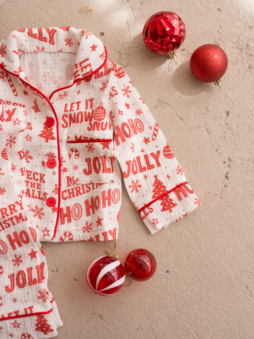 Twas the Night family Christmas pyjamas, white cotton muslin with a red Christmas print, kids long sleeve sleep shirt and pants laid flat, close on the pocket and piping - Before & Ever Kids