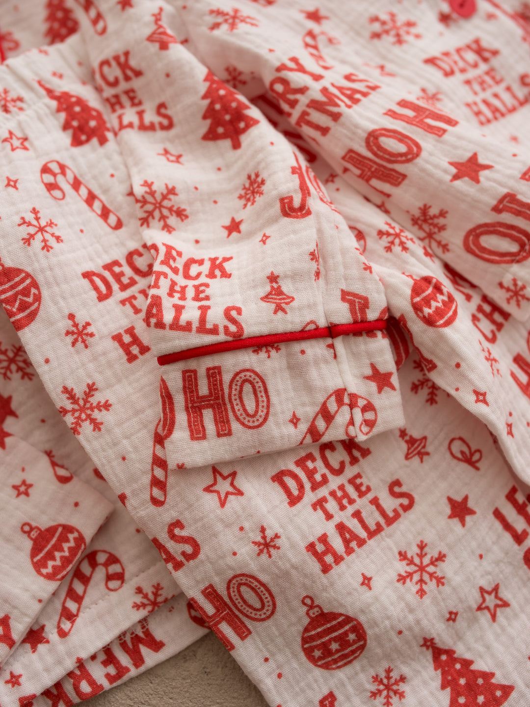 Twas the Night family Christmas pyjamas, white cotton muslin with a red Christmas print, close up of the Deck the Halls print and red piped pocket - Before & Ever Kids