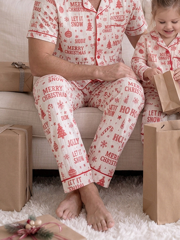 Twas the Night family Christmas pyjamas, white cotton muslin with a red Christmas print, close crop of dad's long pants seated on the sofa with the girl beside him - Before & Ever Kids