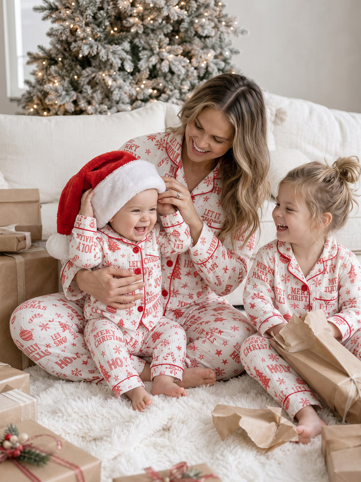 Twas the Night family Christmas pyjamas, white cotton muslin with a red Christmas print, mum in the long sleeve shirt and long pants with the baby in a Santa hat and the girl in long sleeves - Before & Ever Kids