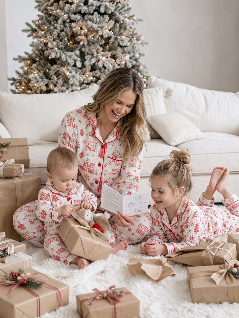 Twas the Night family Christmas pyjamas, white cotton muslin with a red Christmas print, mum, girl and baby on the rug with presents - Before & Ever Kids