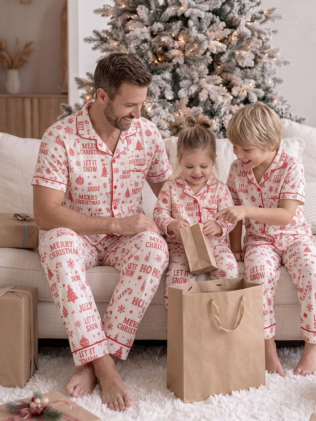 Twas the Night family Christmas pyjamas, white cotton muslin with a red Christmas print, close crop of dad's long pants seated on the sofa with the girl beside him - Before & Ever Kids