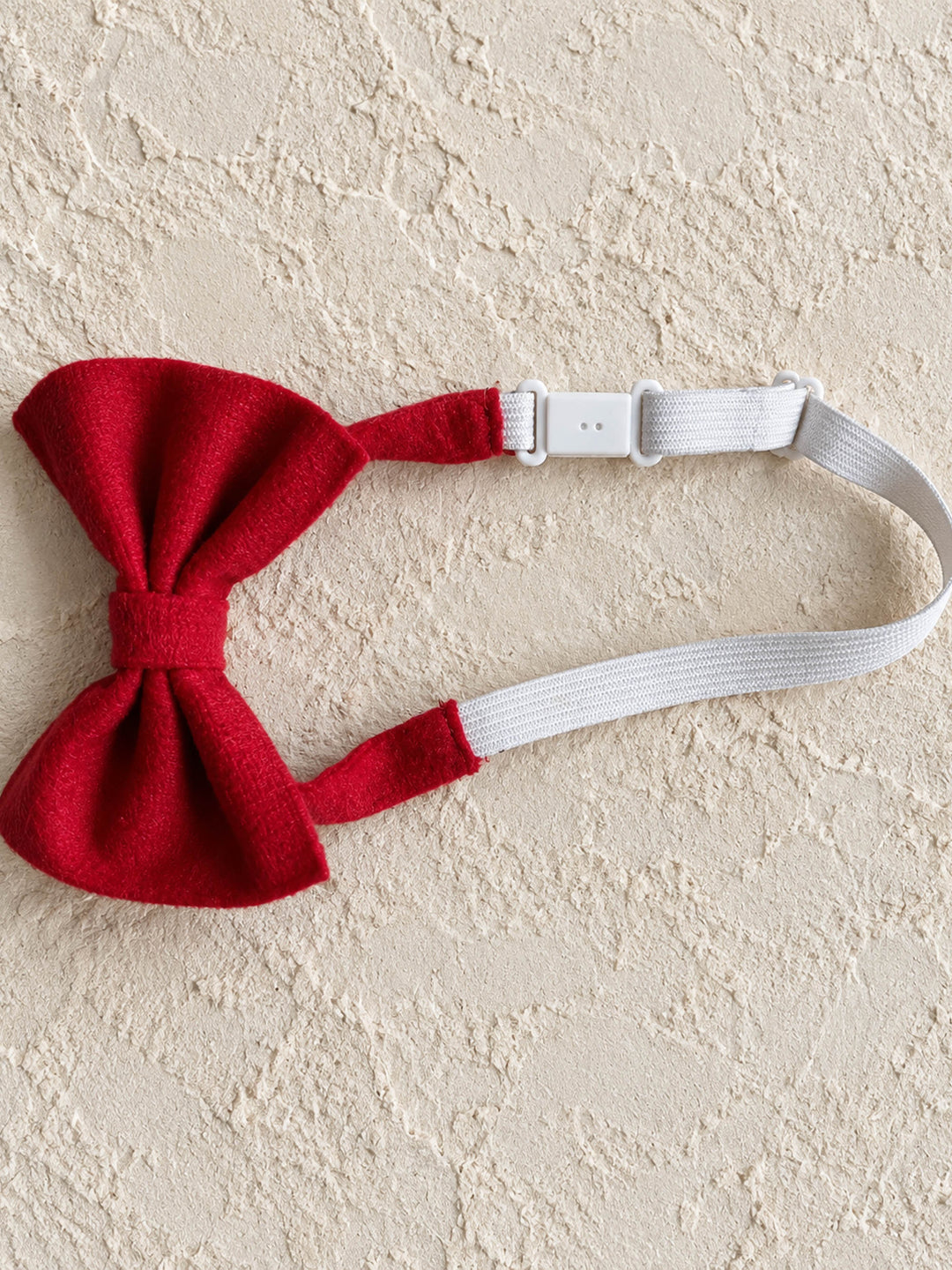 Velvet Bow Tie in red, laid flat with its adjustable white neck strap - Before & Ever Kids