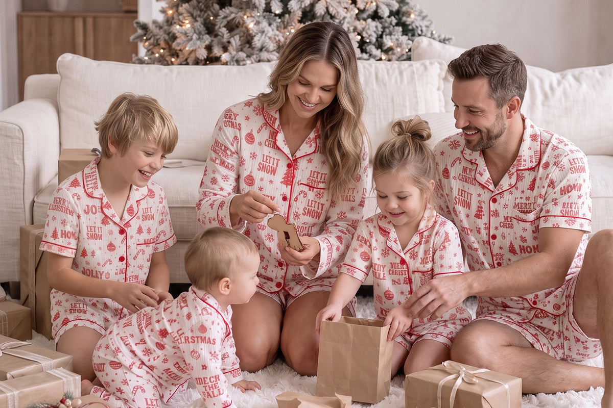 Family in matching Twas the Night Christmas pyjamas opening presents by the tree - Before & Ever Kids